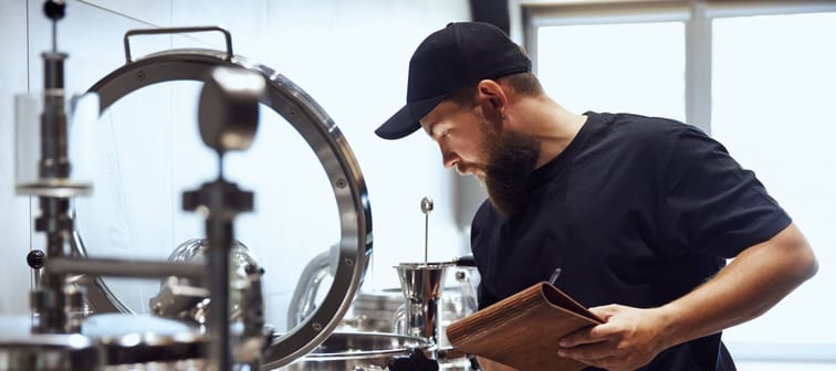 Bearded man checking brewing equipment.