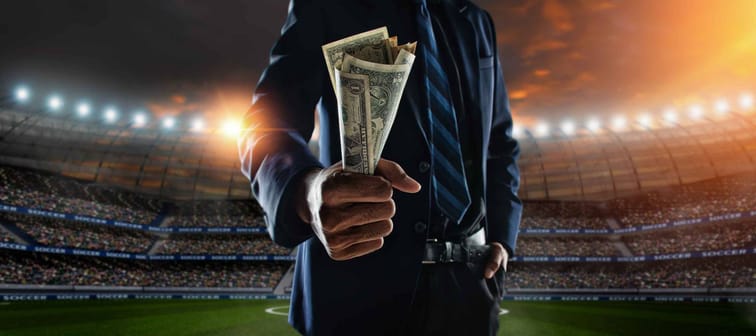 businessman holding large amount of bills at stadium