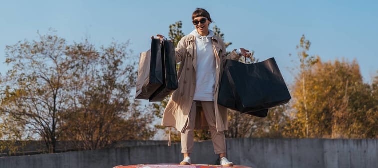 Woman staning on car with shopping bags