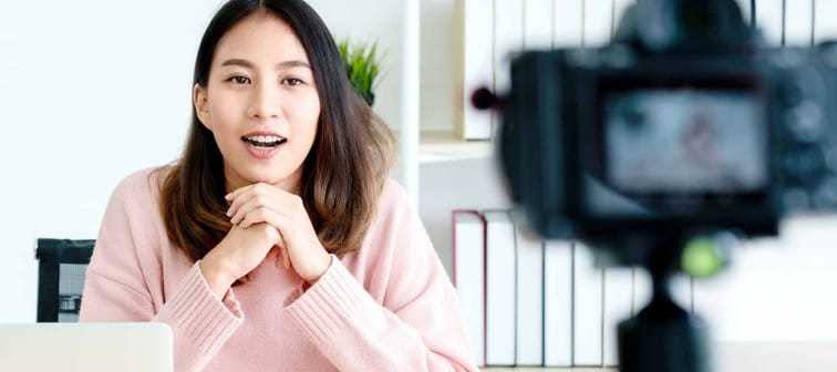 Young asian woman vlogger looking at camera and talking on video