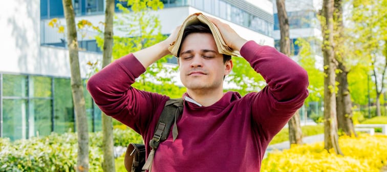 Young man covers his head with a book