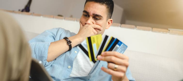 Man holding four credit cards looking at his computer