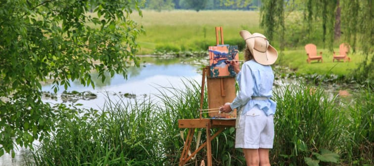 Woman outdoors painting s landscape.
