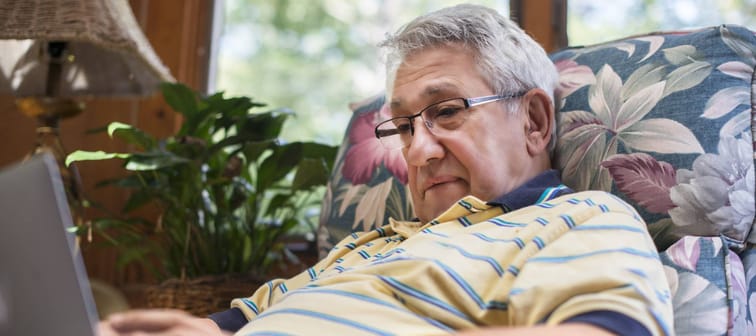 Senior man, sitting at home, using laptop