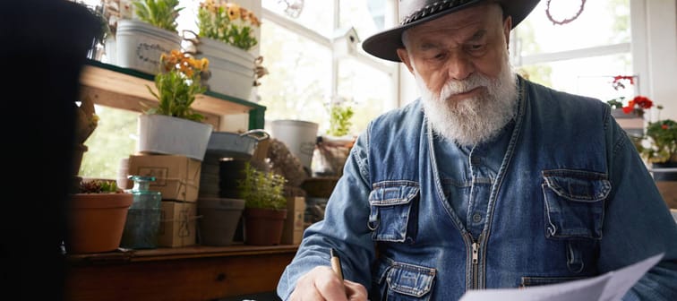 Elderly male florist working with documents in shop.
