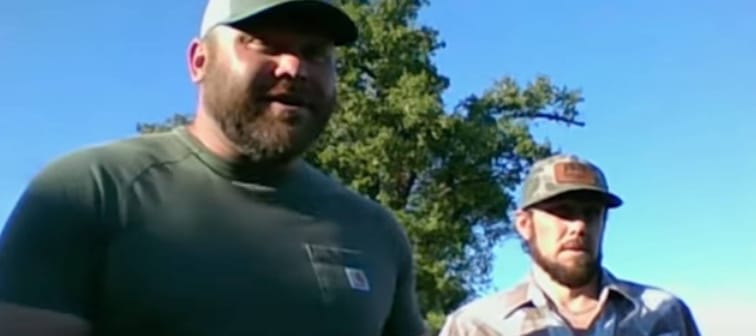 Two brothers speak on camera in front of a tree.