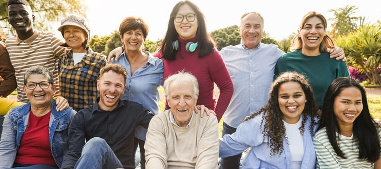 Multigenerational group of diverse people smiling outside.