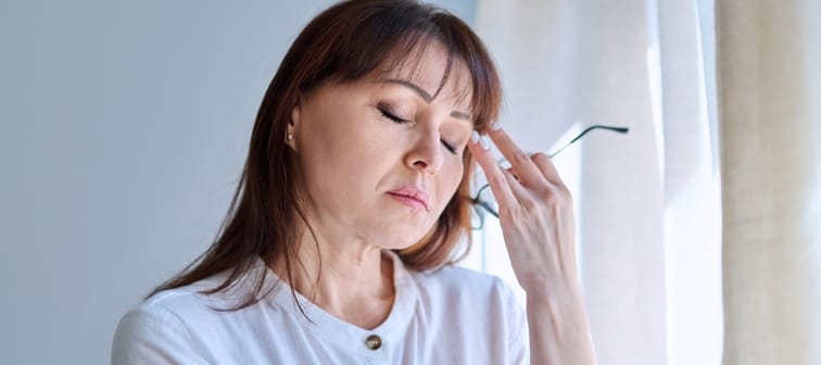 Middle-aged woman experiencing stress with her hand to her forehead.
