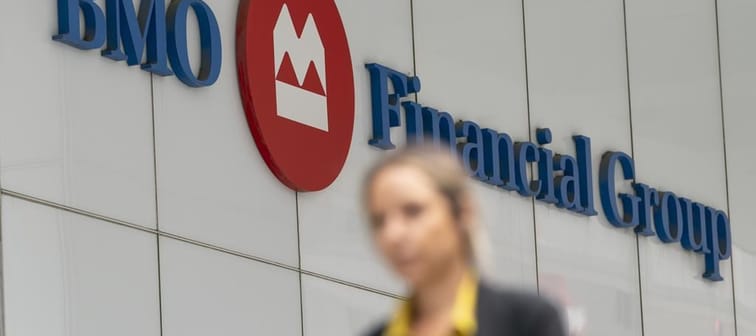 BMO Financial Group says it will close its retail auto finance business in order to reroute resources following a rise in bad debt. A person makes their way past the Bank of Montreal (BMO) bu