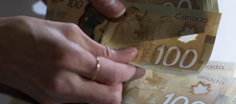 A new survey by consulting firm Eckler suggests wage increases in Canada in 2024 will edge lower compared what has been seen this year. Canadian $100 bills are counted in Toronto, Feb. 2, 201