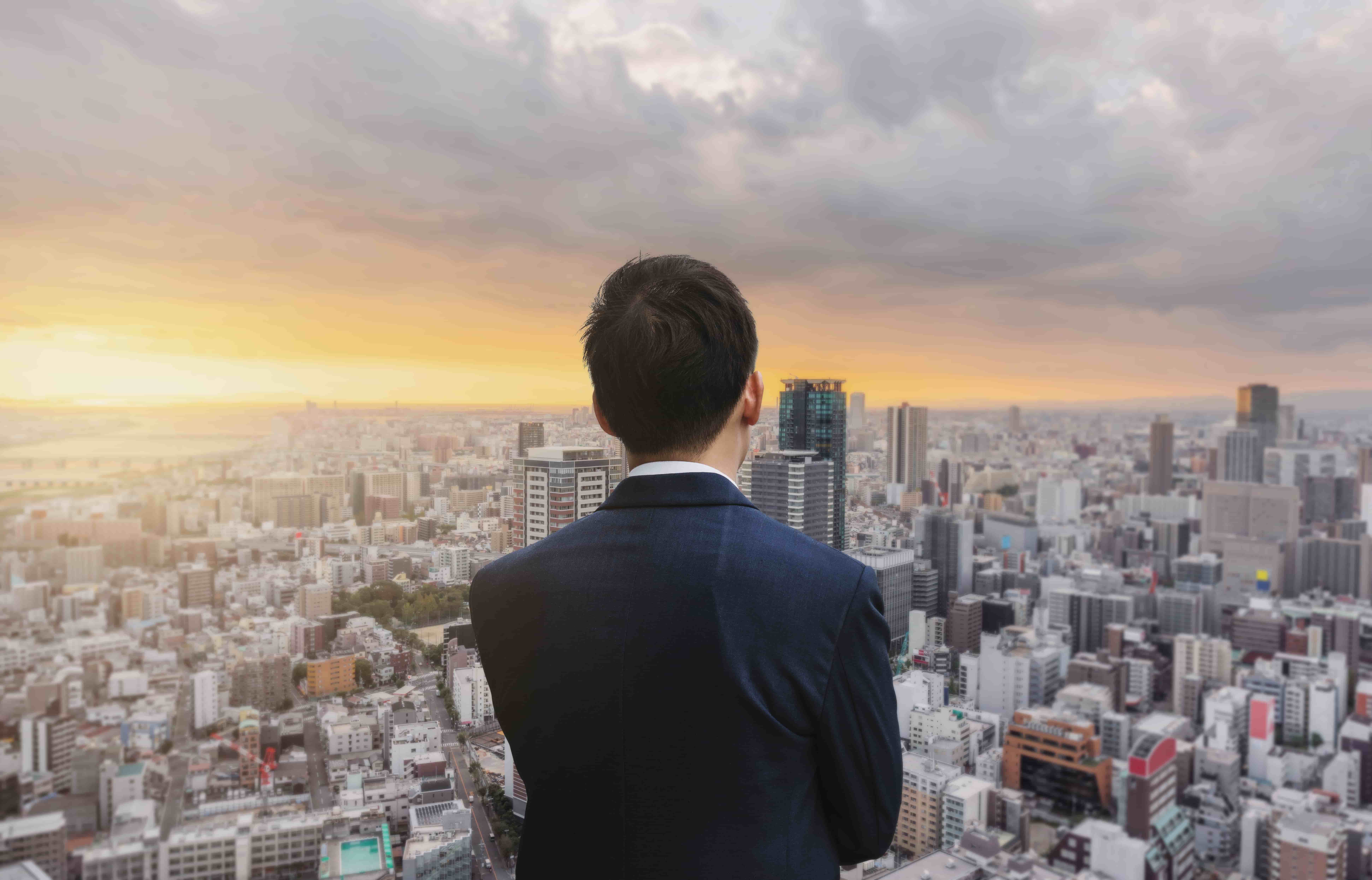Businessman in blue suit and cityscape in sunrise