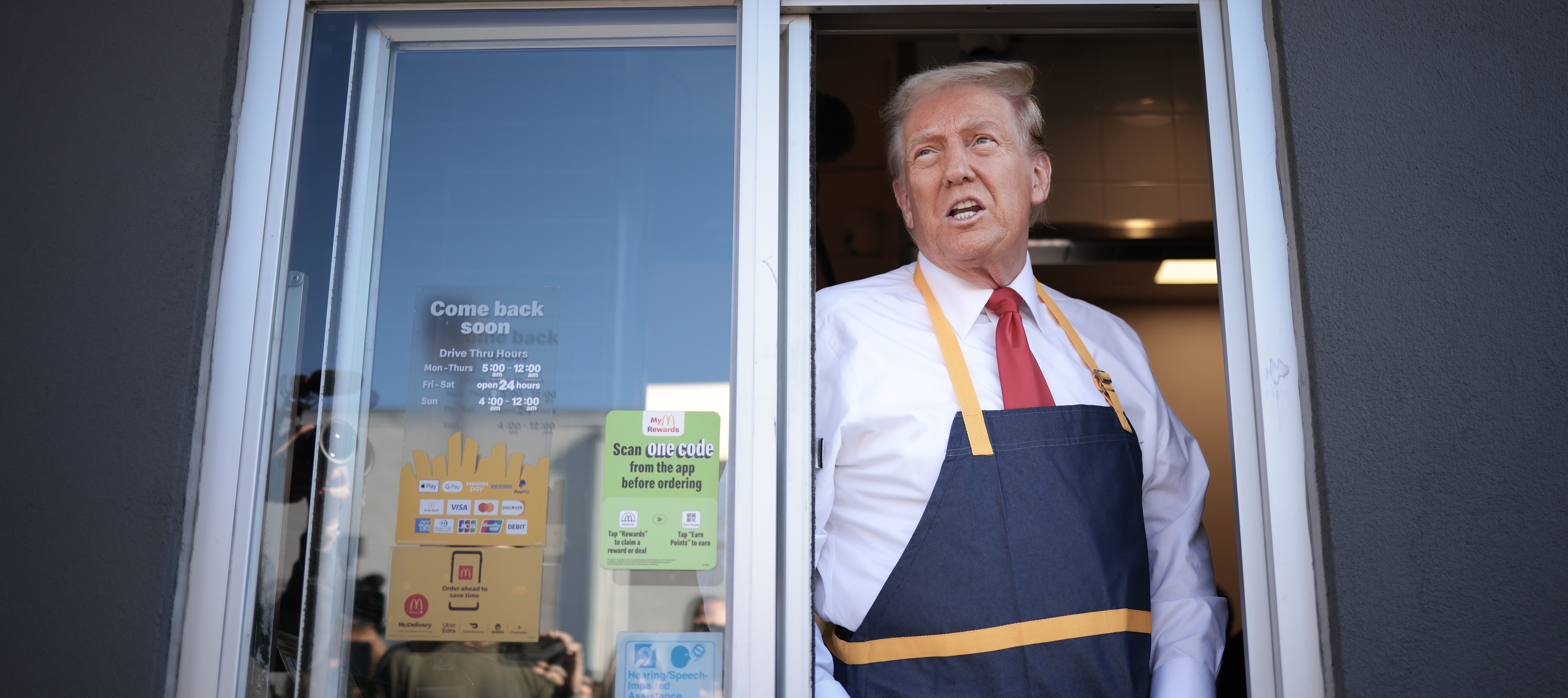 President Donald Trump works the drive-through line during a campaign photo op as he visits a McDonald's restaurant.