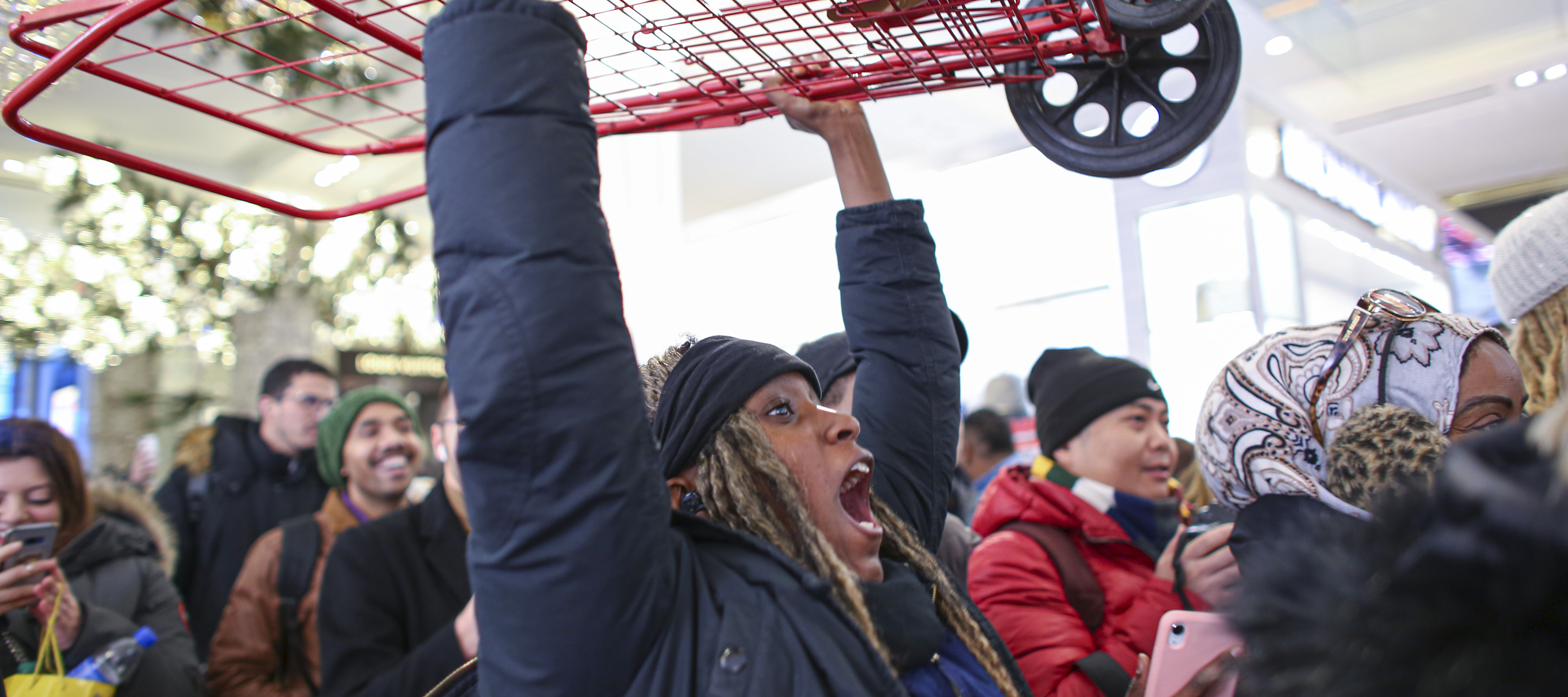 A woman exclaims while holding a shopping cart over her head as Black Friday sales begin.