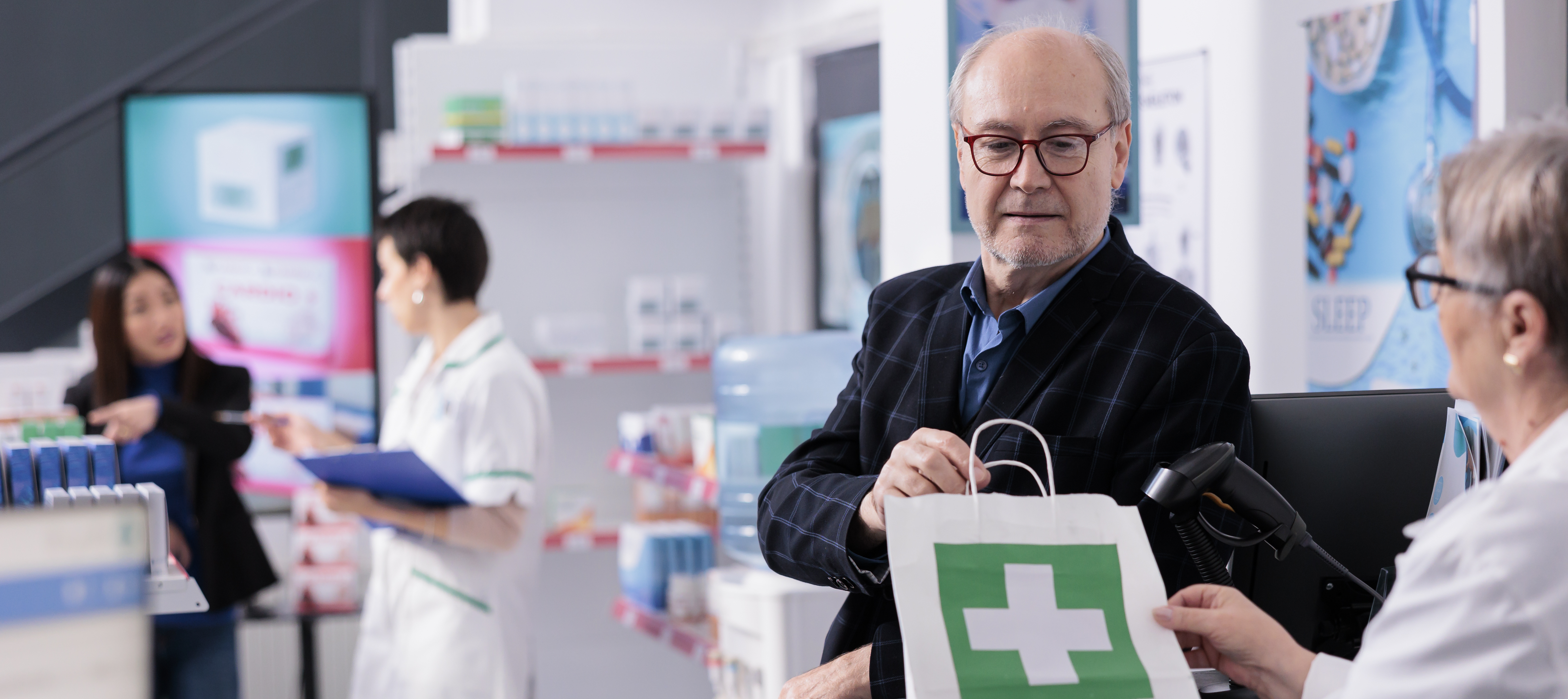 Man receiving a bag medication at pharmacy desk.