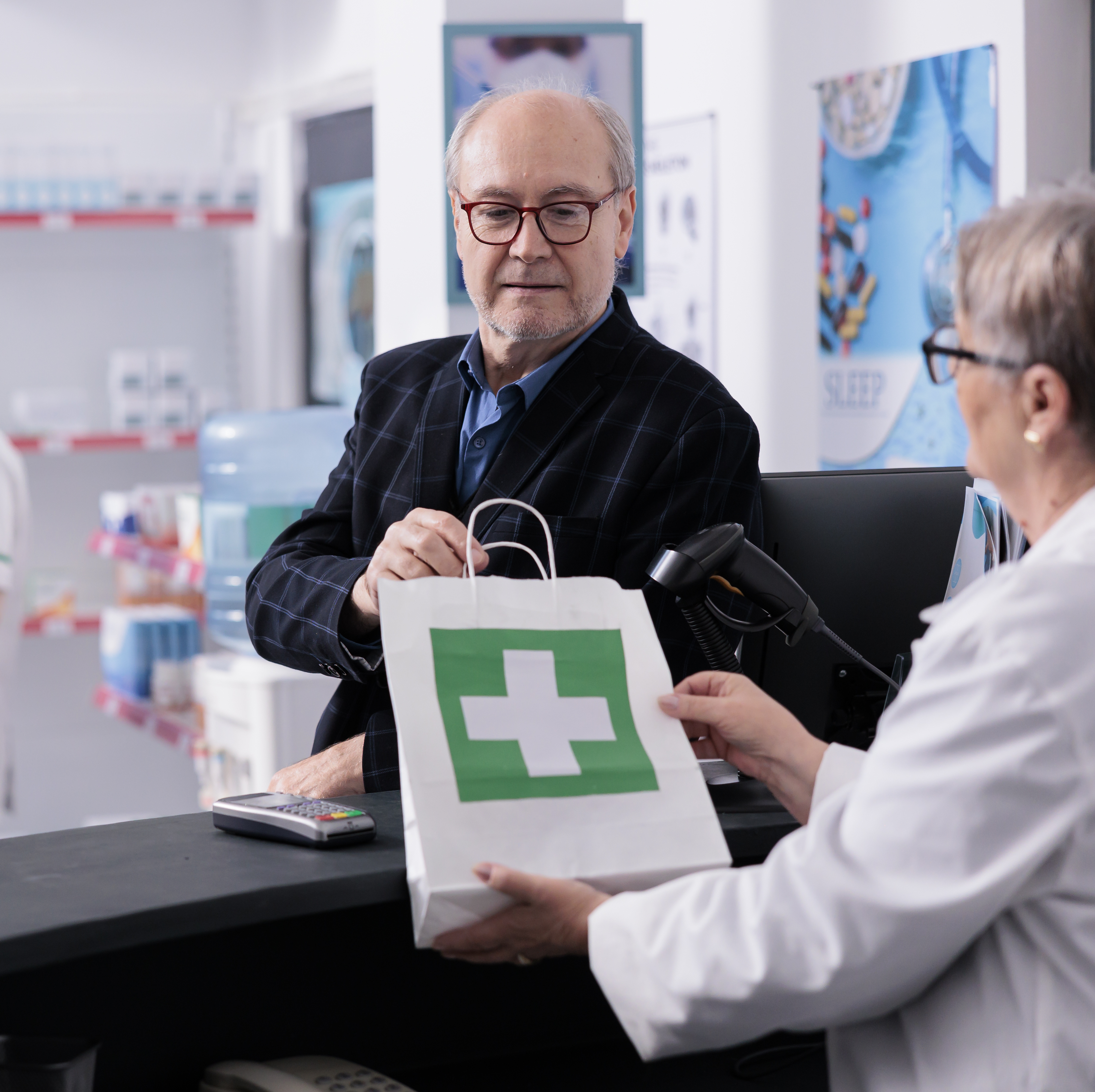 Man receiving a bag medication at pharmacy desk.