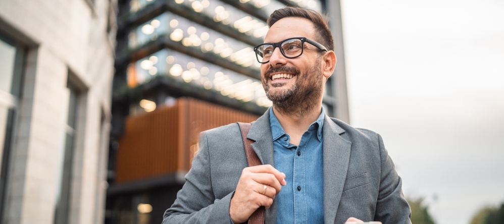Smiling businessman standing in front of modern building.