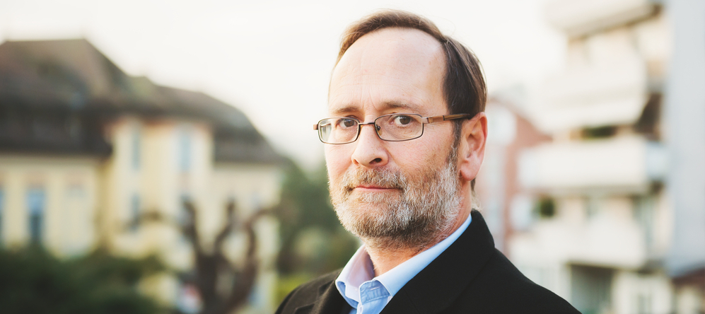 Outdoor portrait of 50 year old man wearing black coat and eyeglasses