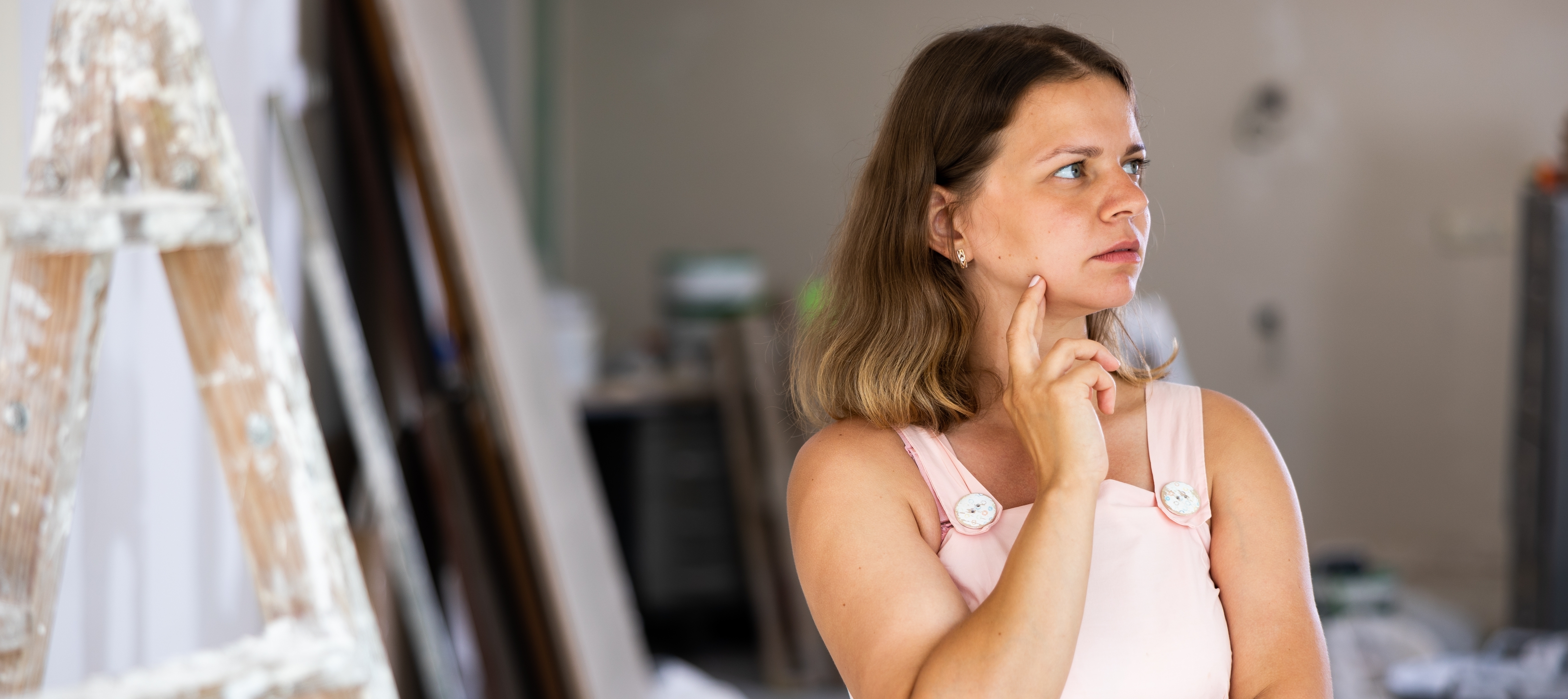 Interview view of an owner of a cottage surveying home remodel work, looking contemplative.
