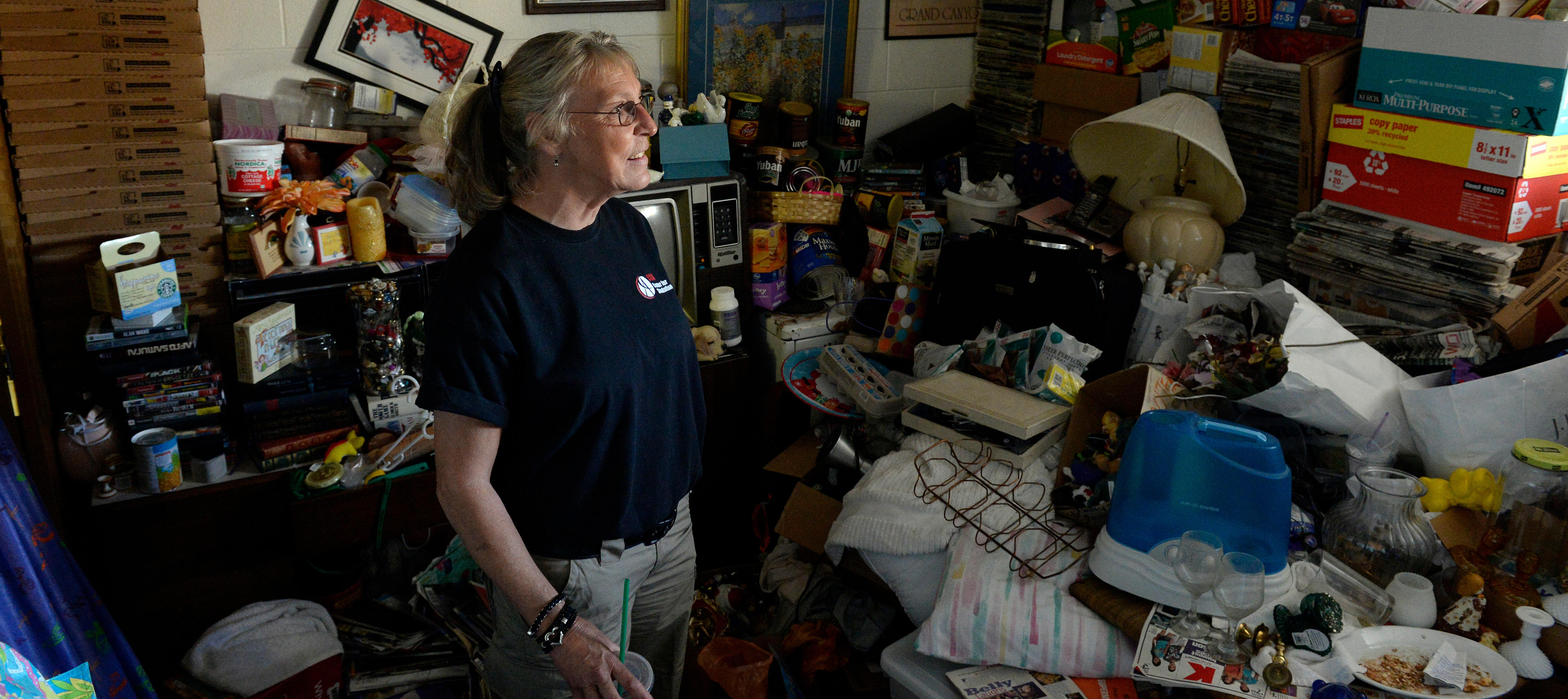 A woman examines the many belongings that occupy one of the rooms in her house.