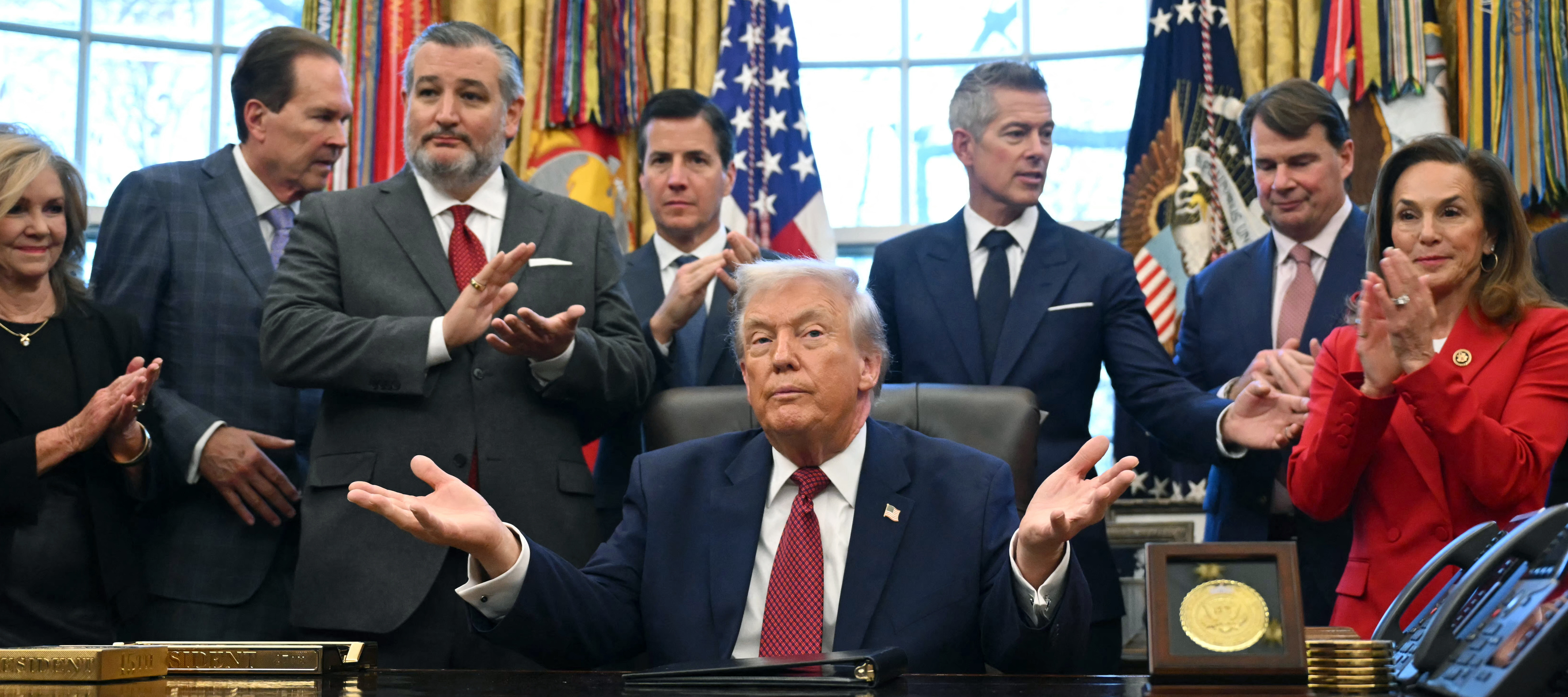 President Trump speaks in the oval office with members of his team at his side.