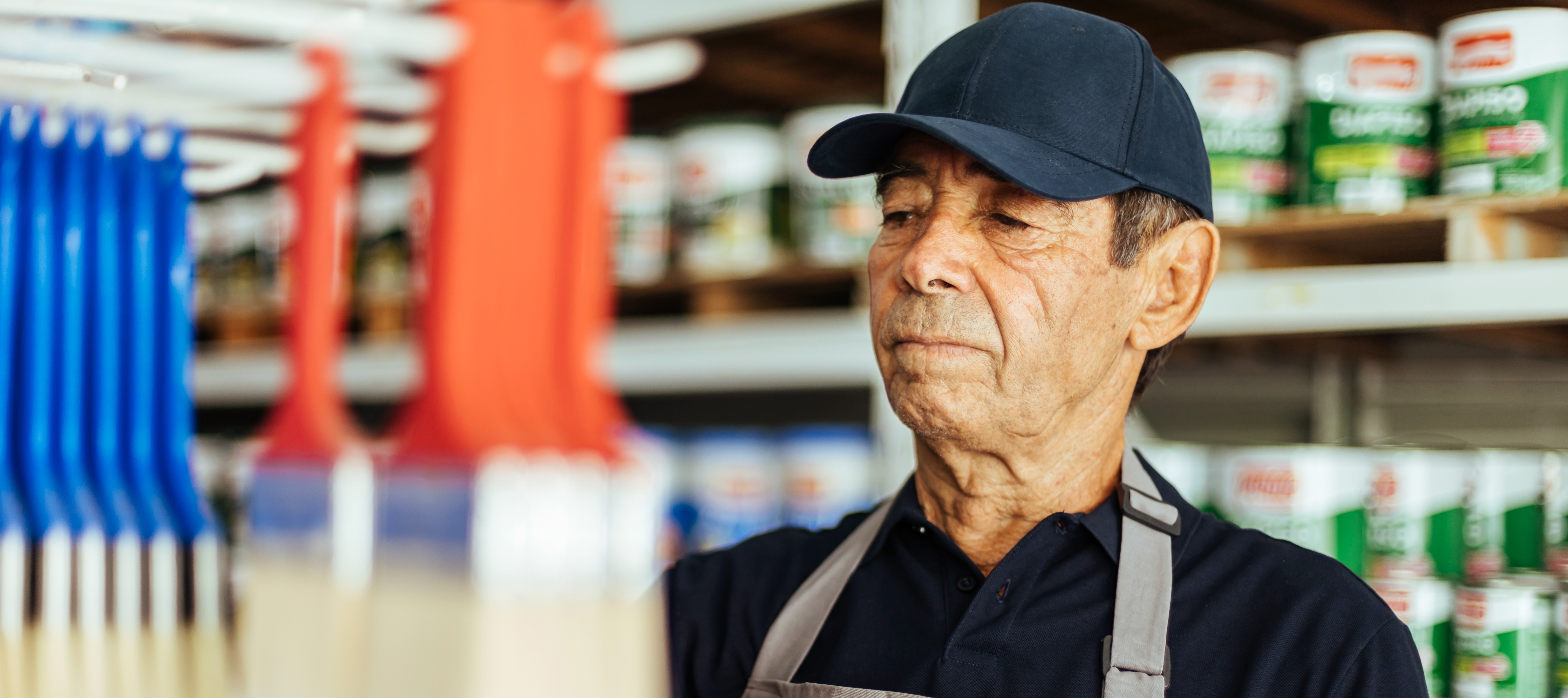 Elderly man working in a hardware store restocking items on shelves.