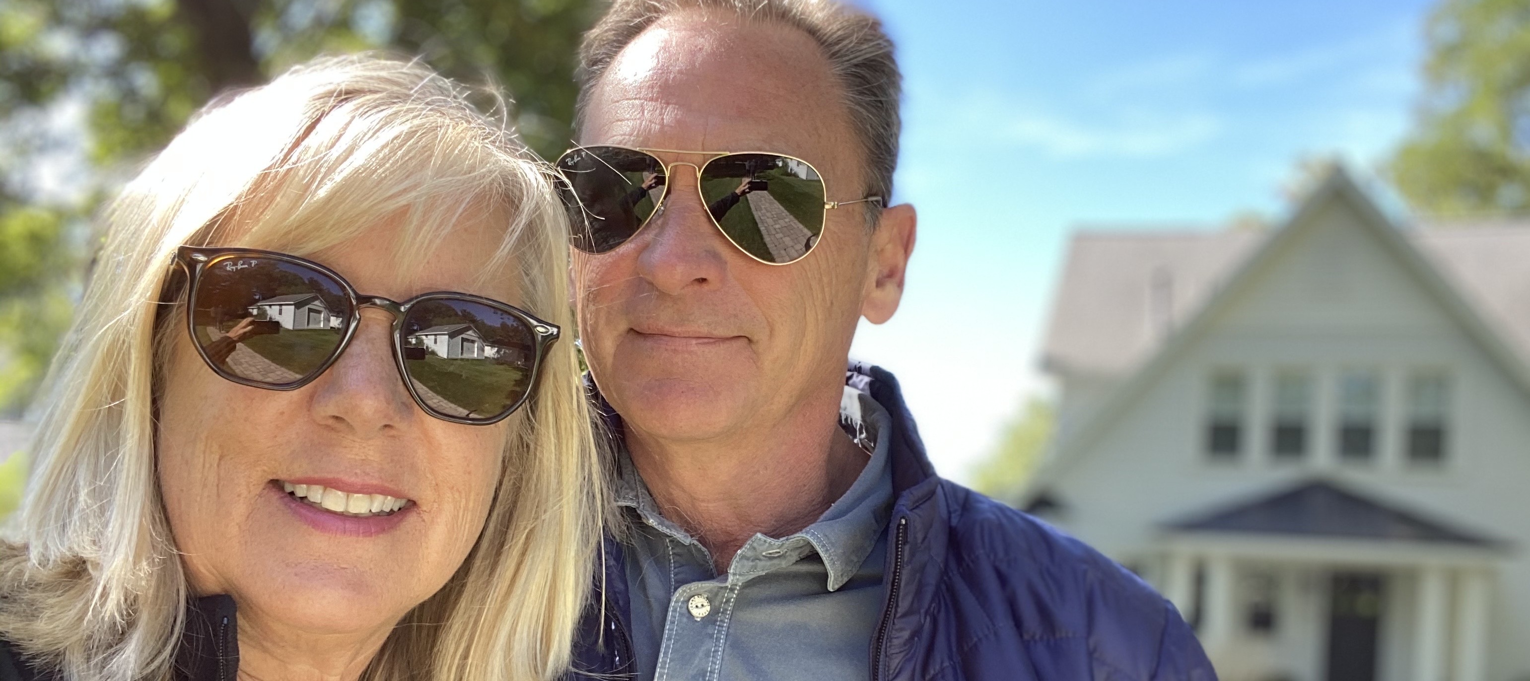 63 year old couple smiling in front of sold house