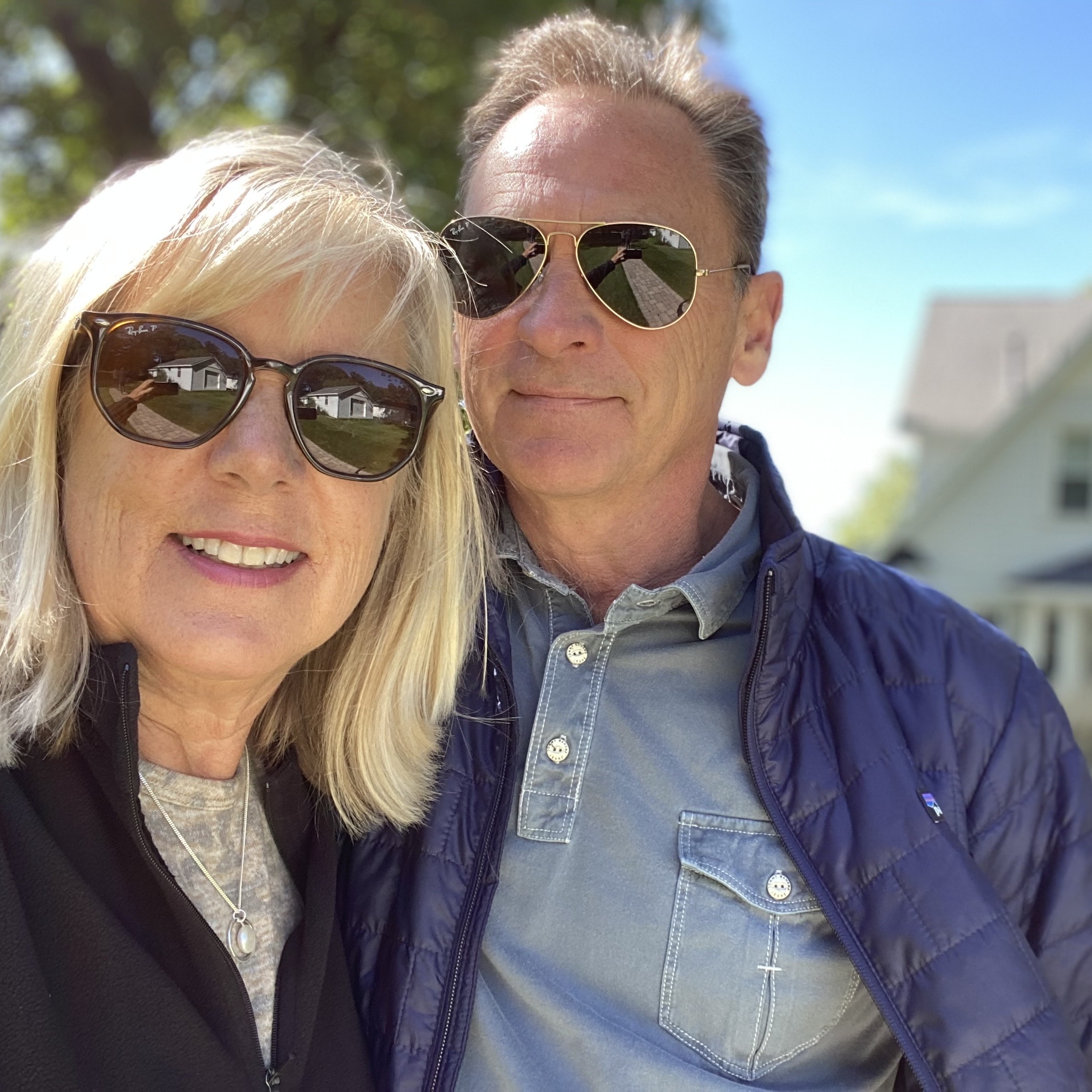 63 year old couple smiling in front of sold house
