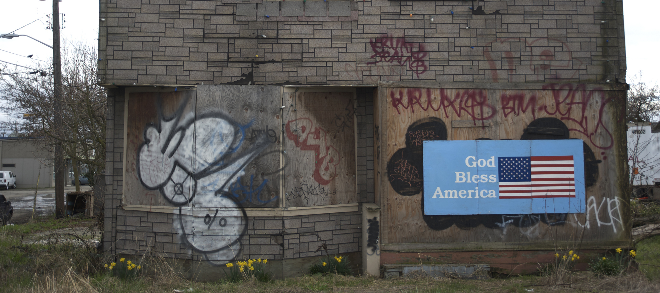 Abandoned home with a sign reading 'God Bless America' on the front.