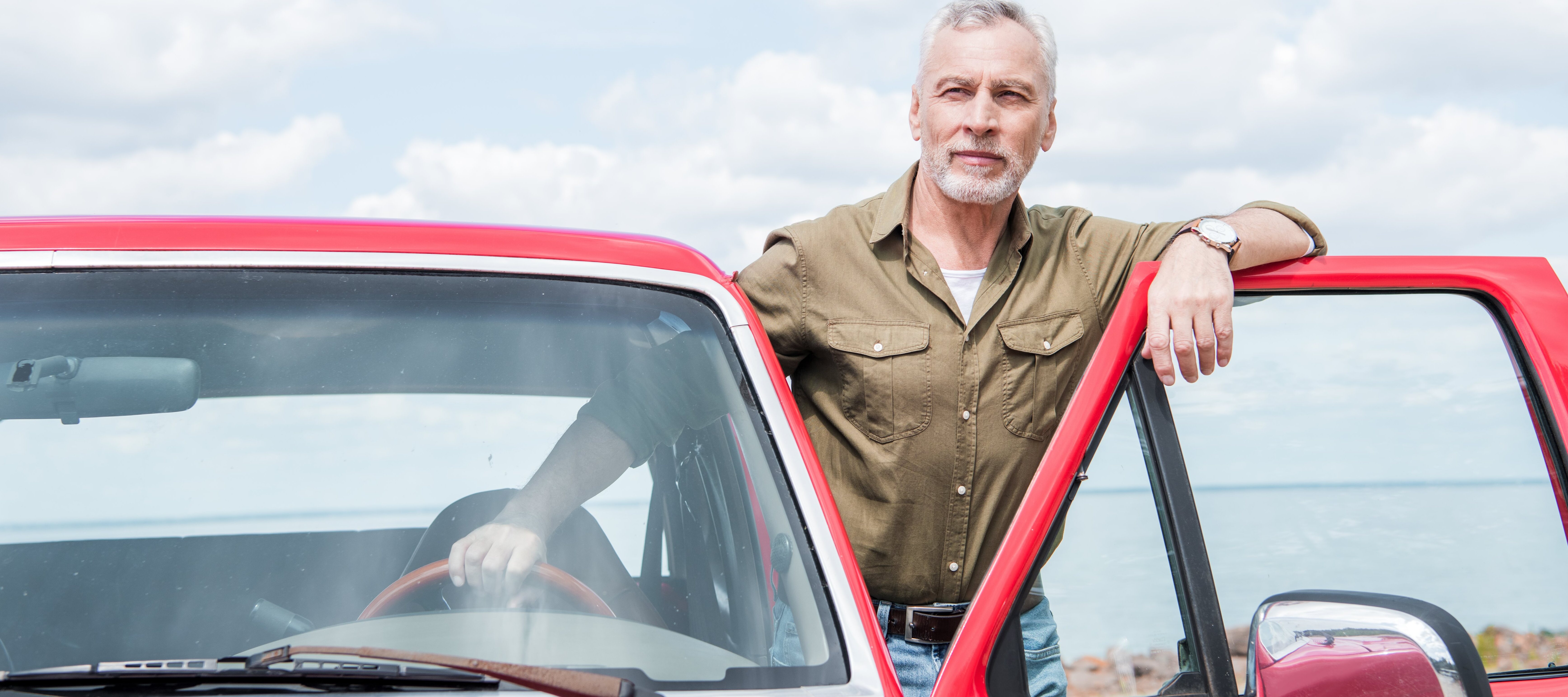 Middle aged man standing in front of fancy red truck.