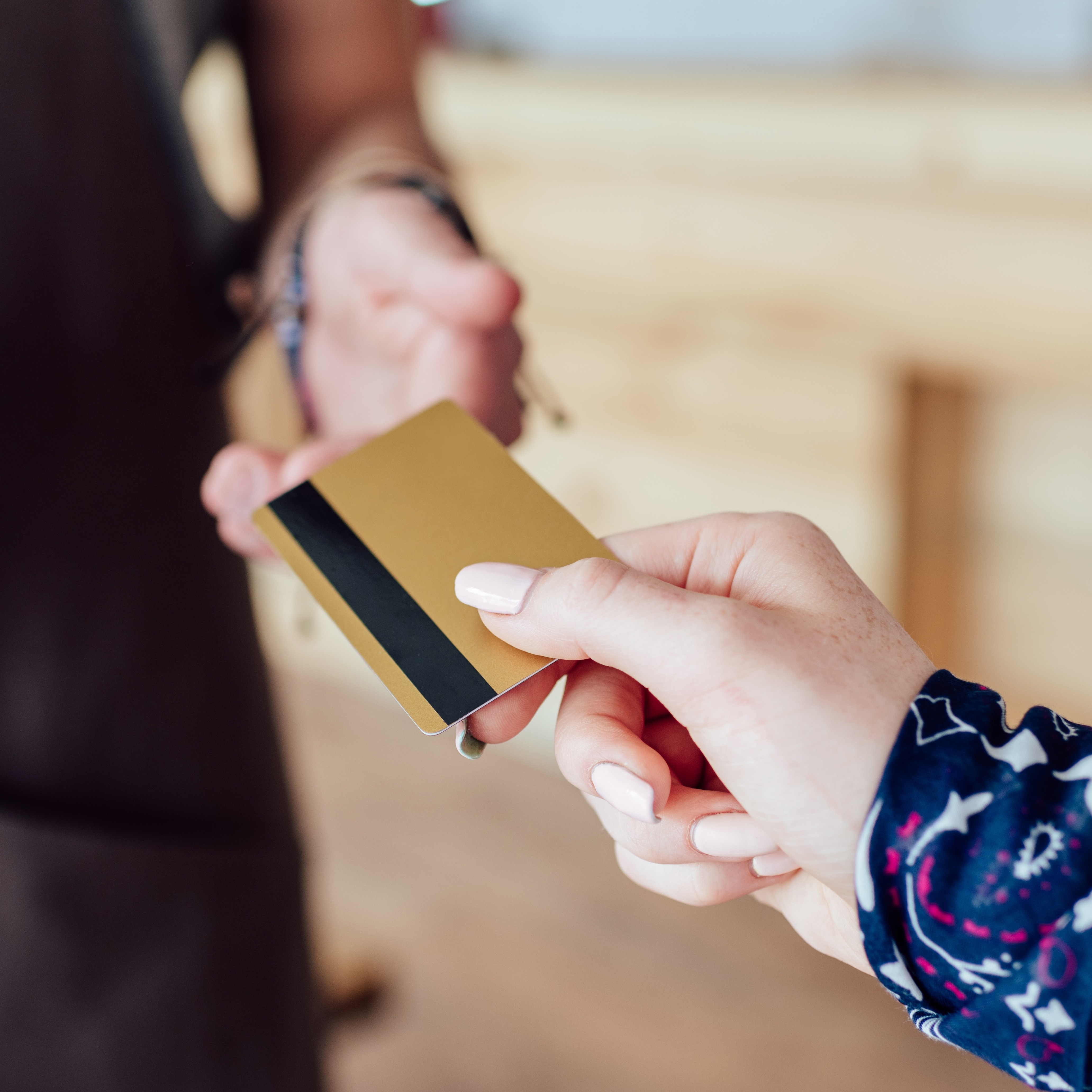 Close up of a person handing their card over to be used for tap payment against a handheld terminal.