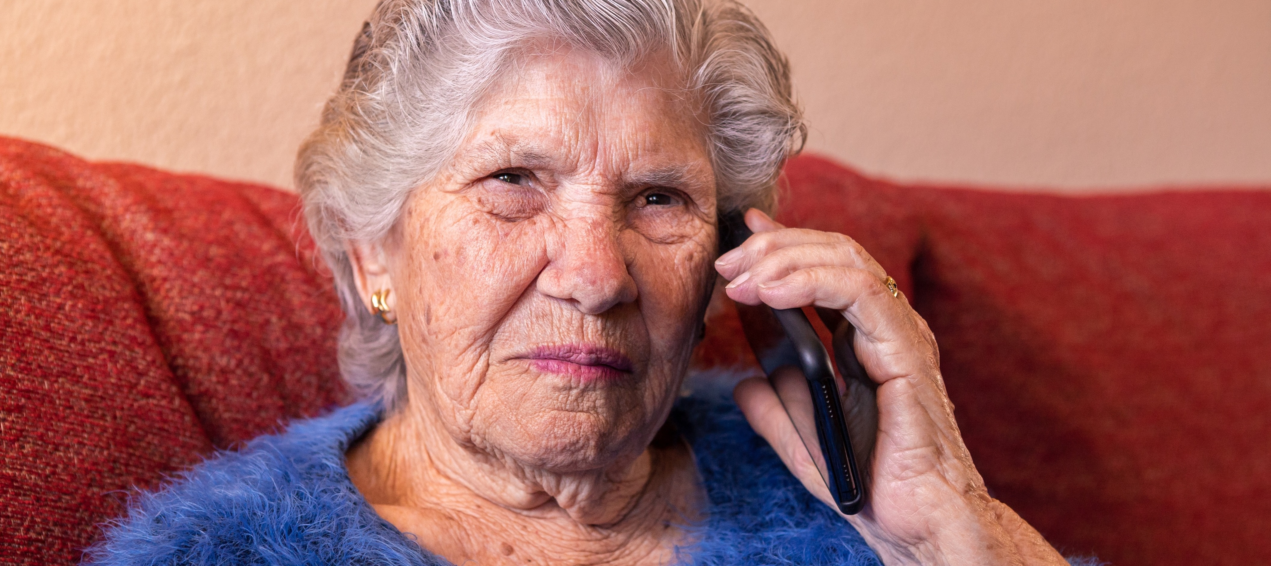 Close up of old woman looking concerned while being scammed on the phone.