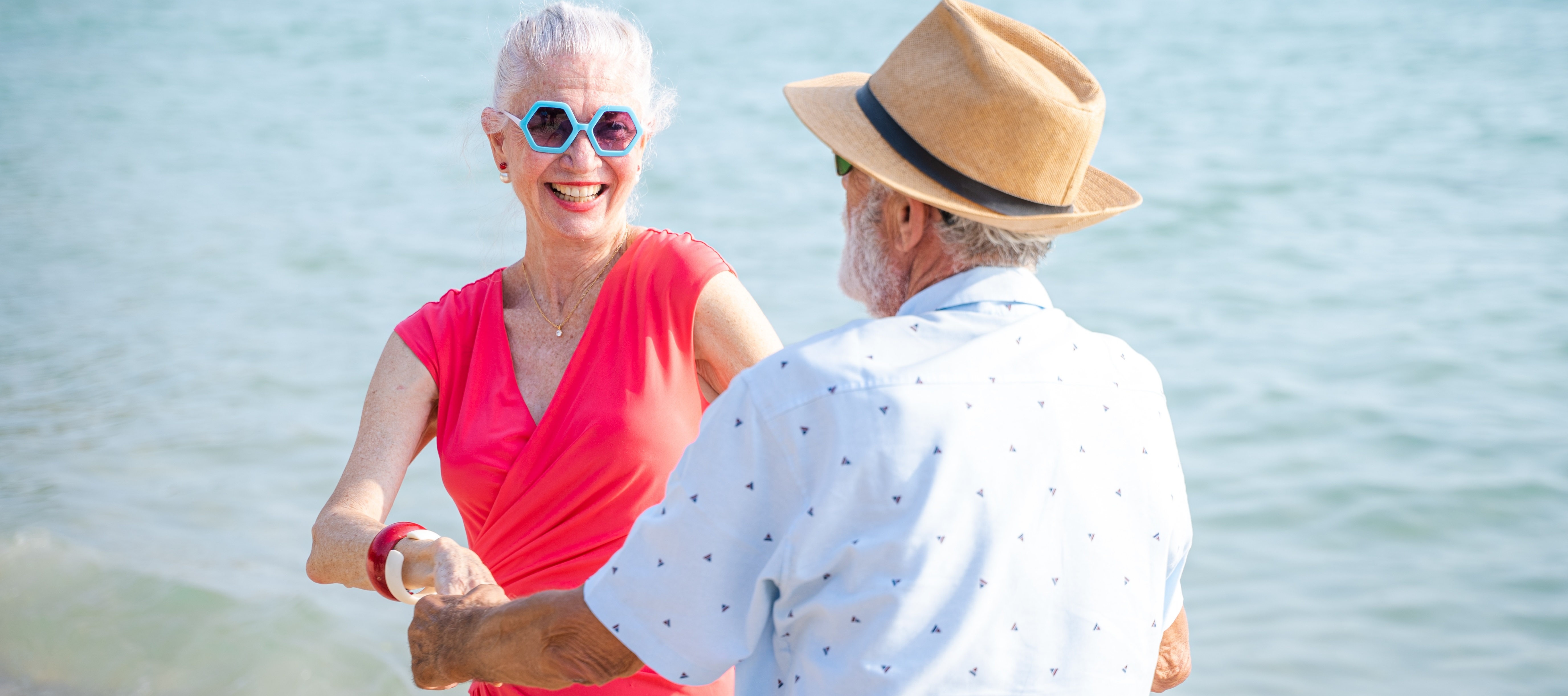 Happy retired couple dancing on a beach.