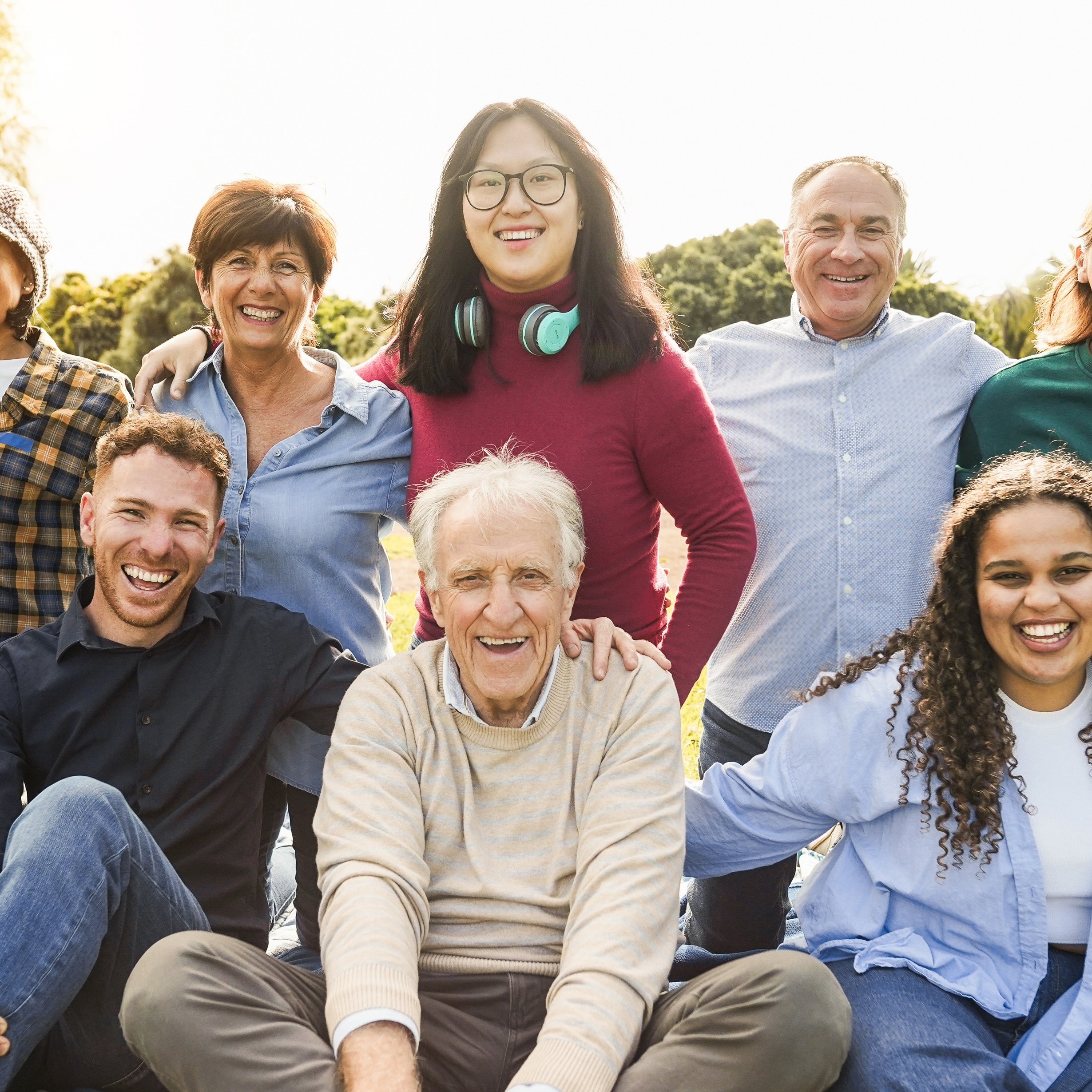 Multigenerational group of diverse people smiling outside.