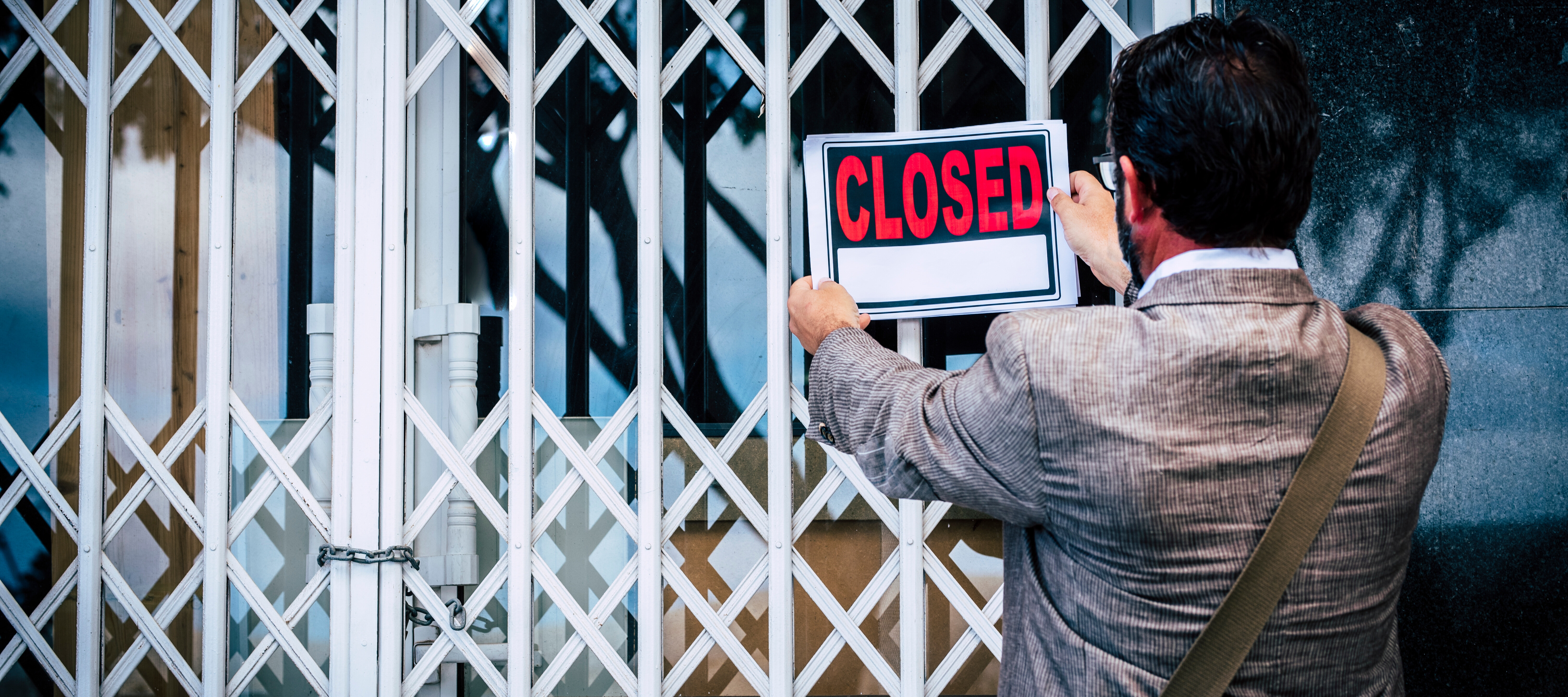 A man places a closed sign on the front door of his business.