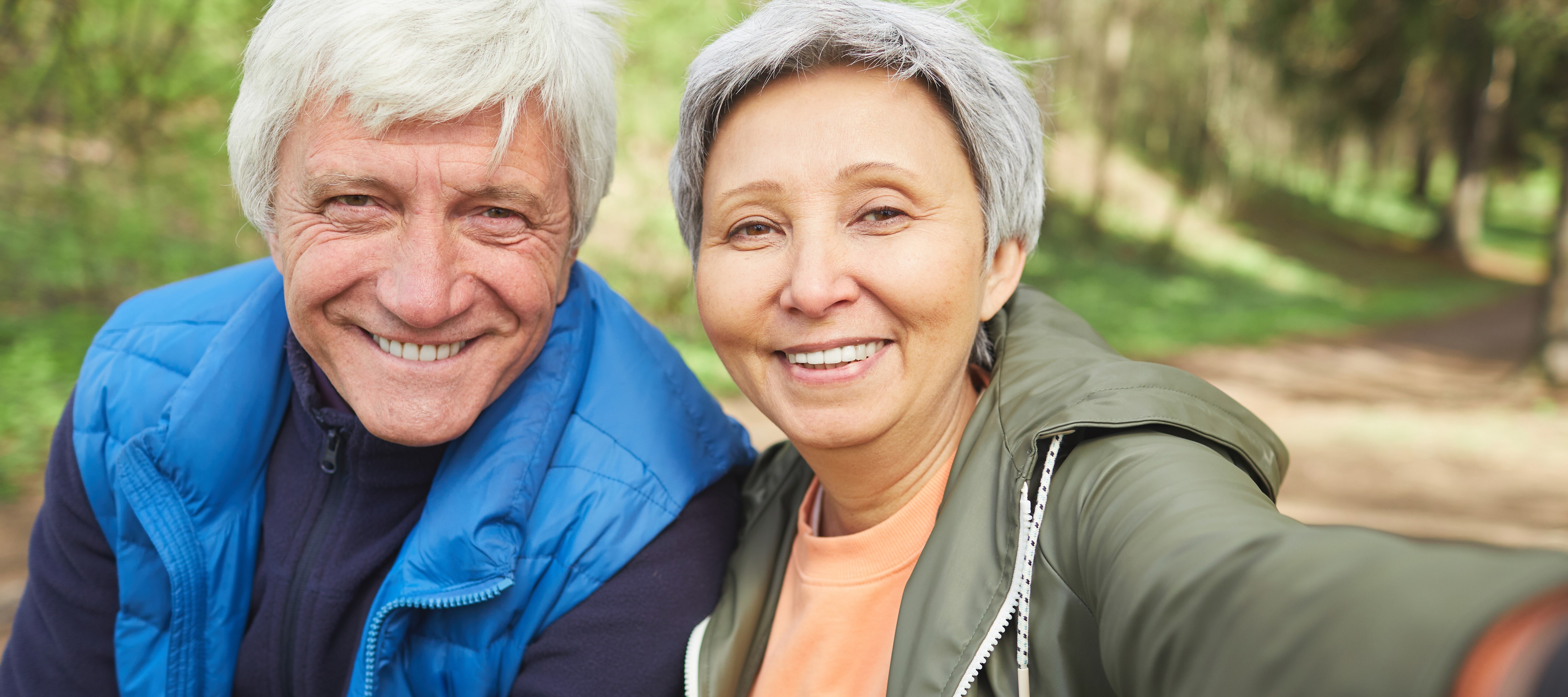 Retired couple smiling on a hike.