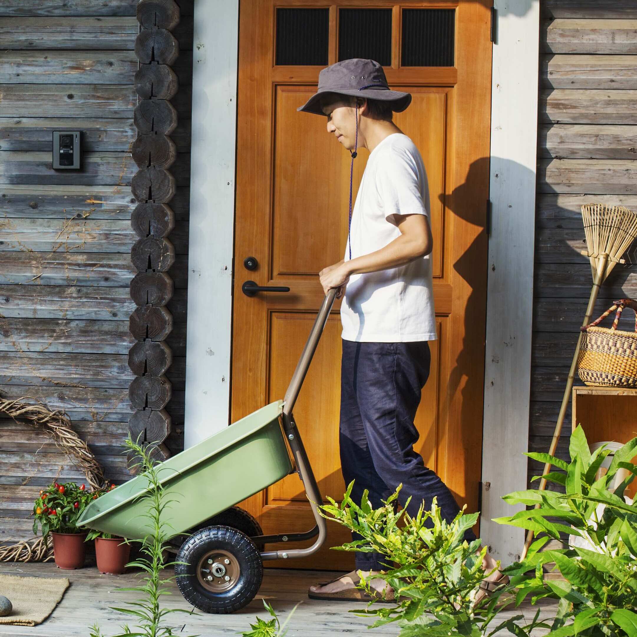 Young woman pushing wheelbarrow outside of childhood home.