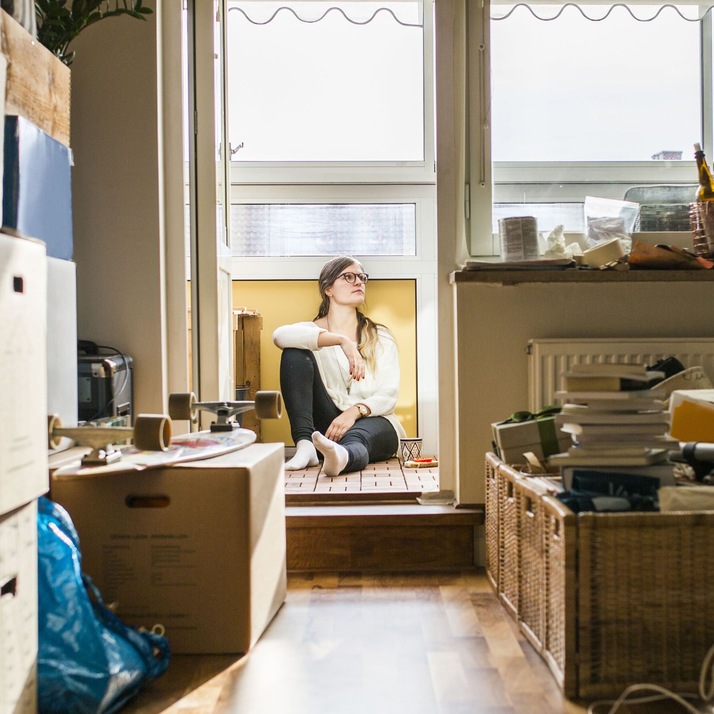 Young woman sitting amongst boxes in her rented apartment.