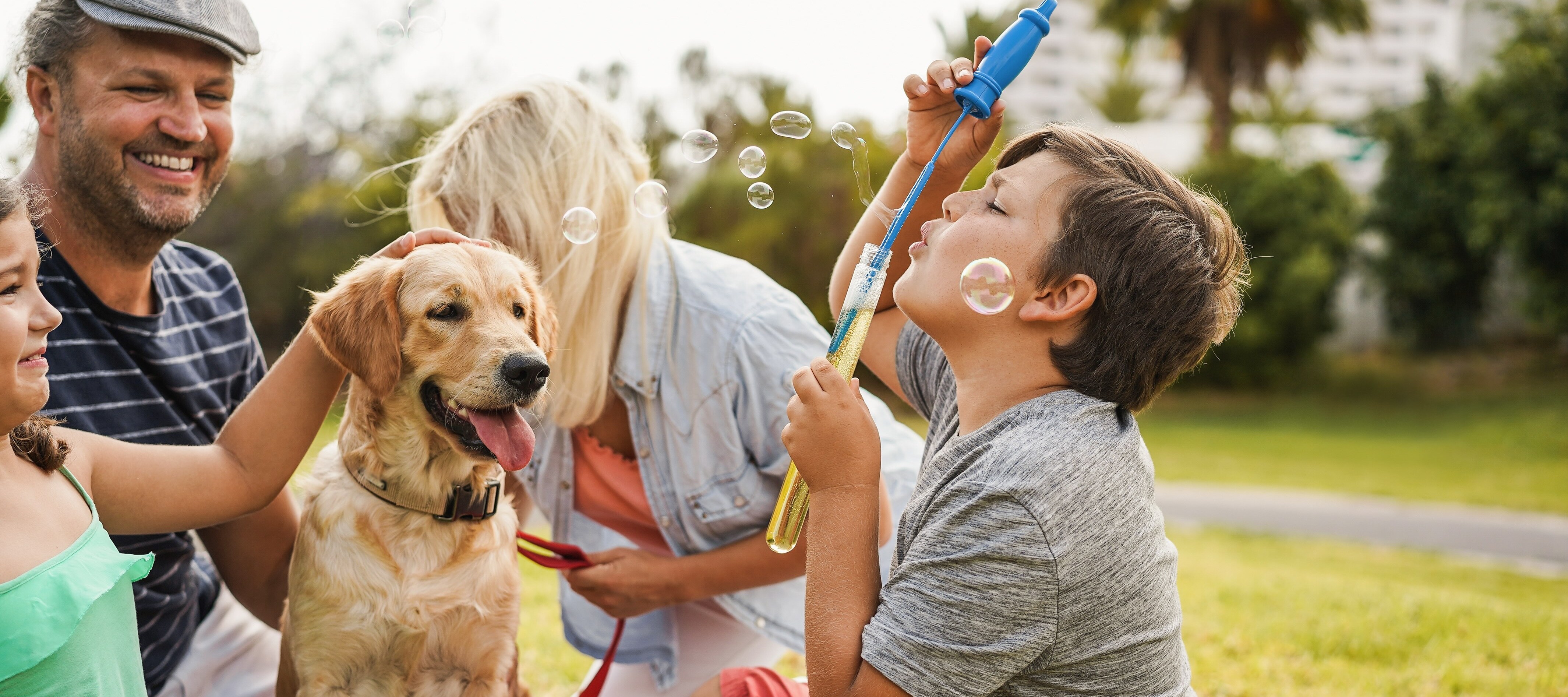 Family blowing bubbles in park with their dog.