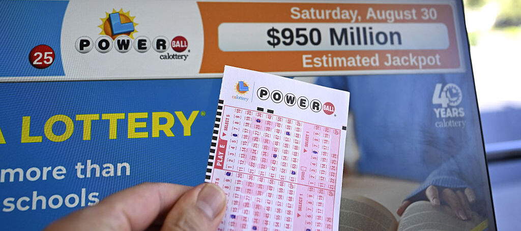 A Powerball lottery ticket and a monitor are seen as U.S. Powerball jackpot grows $950 million in California.