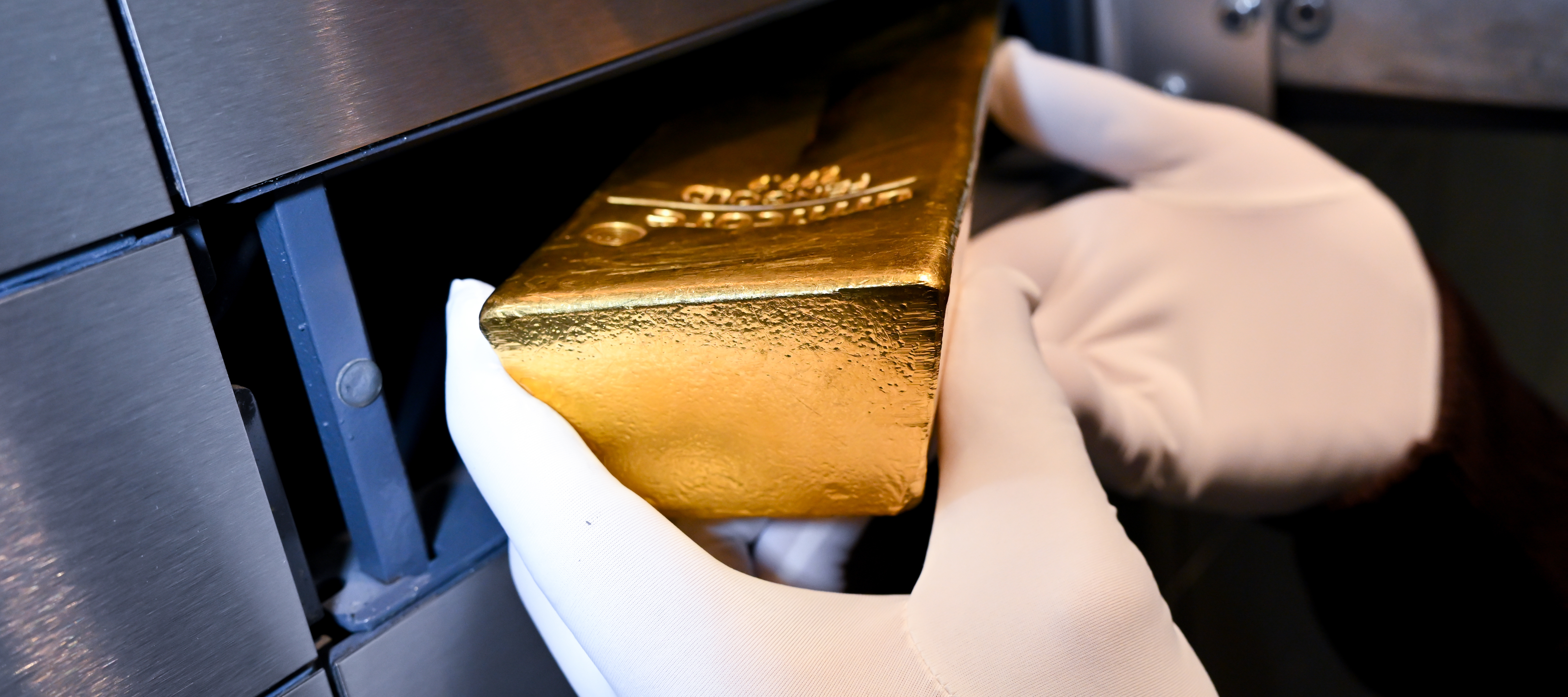 A bank employee removes a gold bar from a safety deposit box.