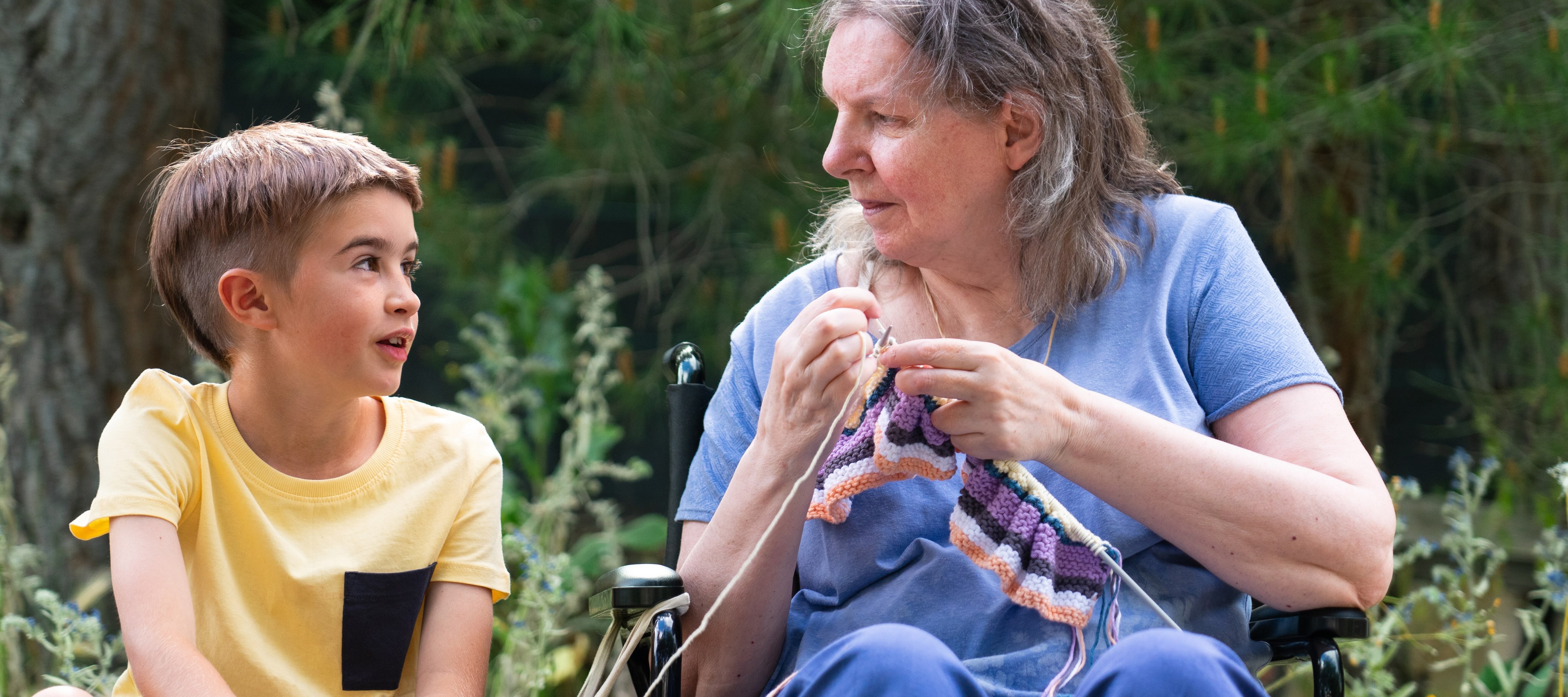 70-year-old woman knitting and talking to her grandchild.