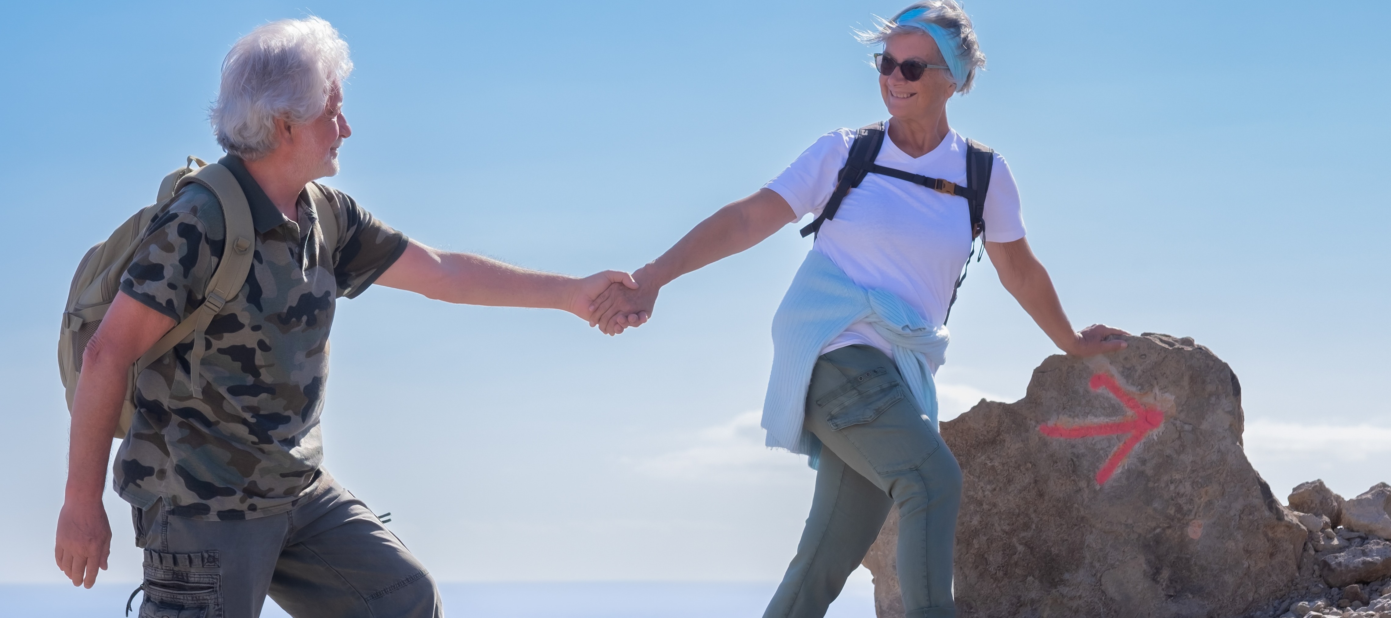 Retired couple holding hands on a hike.