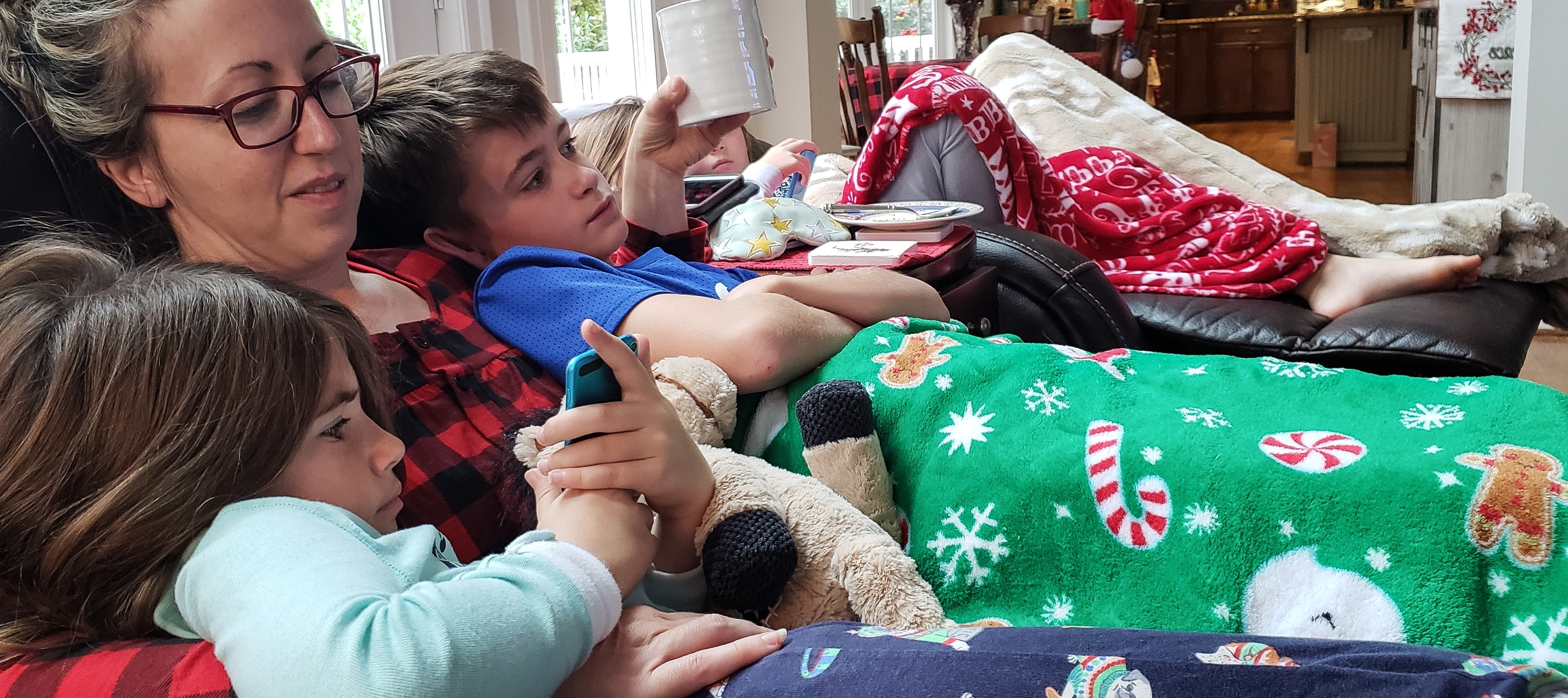 A mother lies under the blankets with her children.
