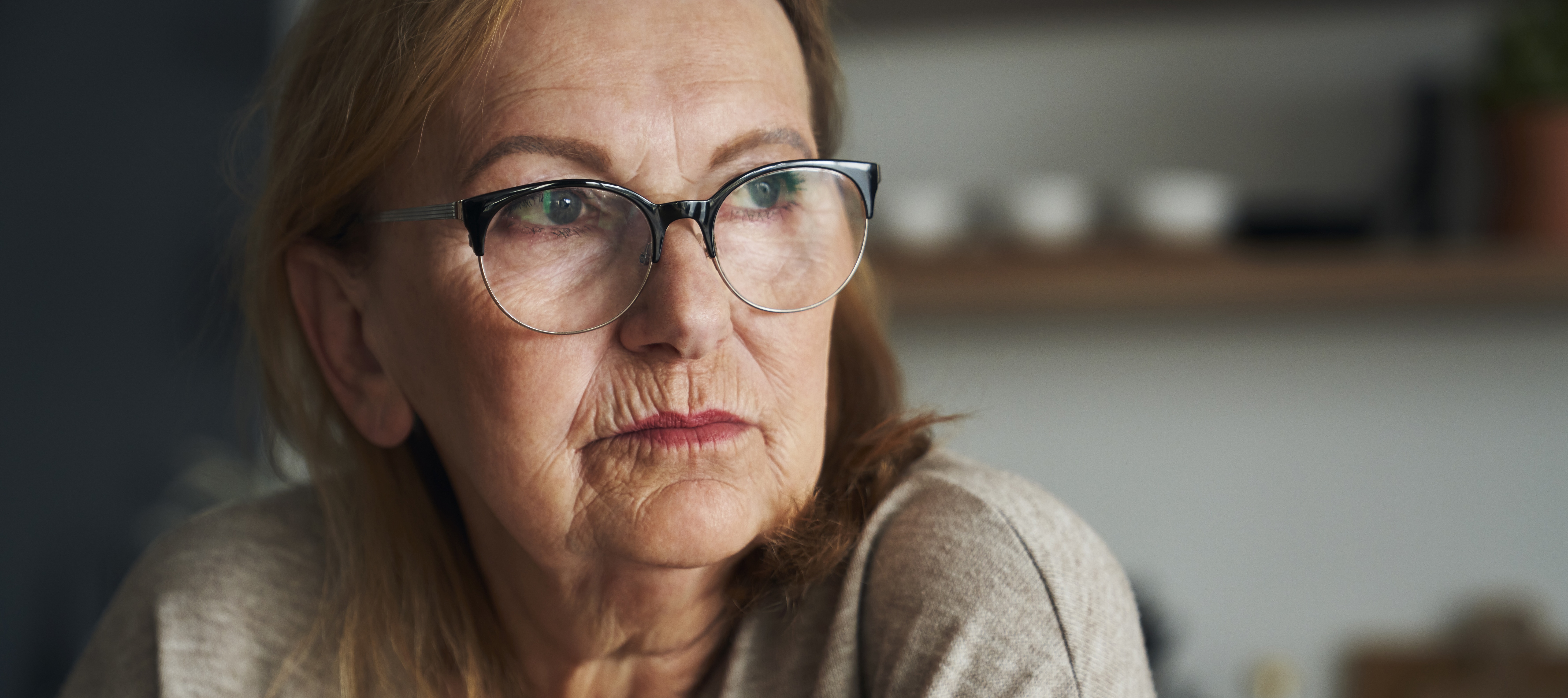 Close up of a pensive, worried senior woman in her home looking off to the side.