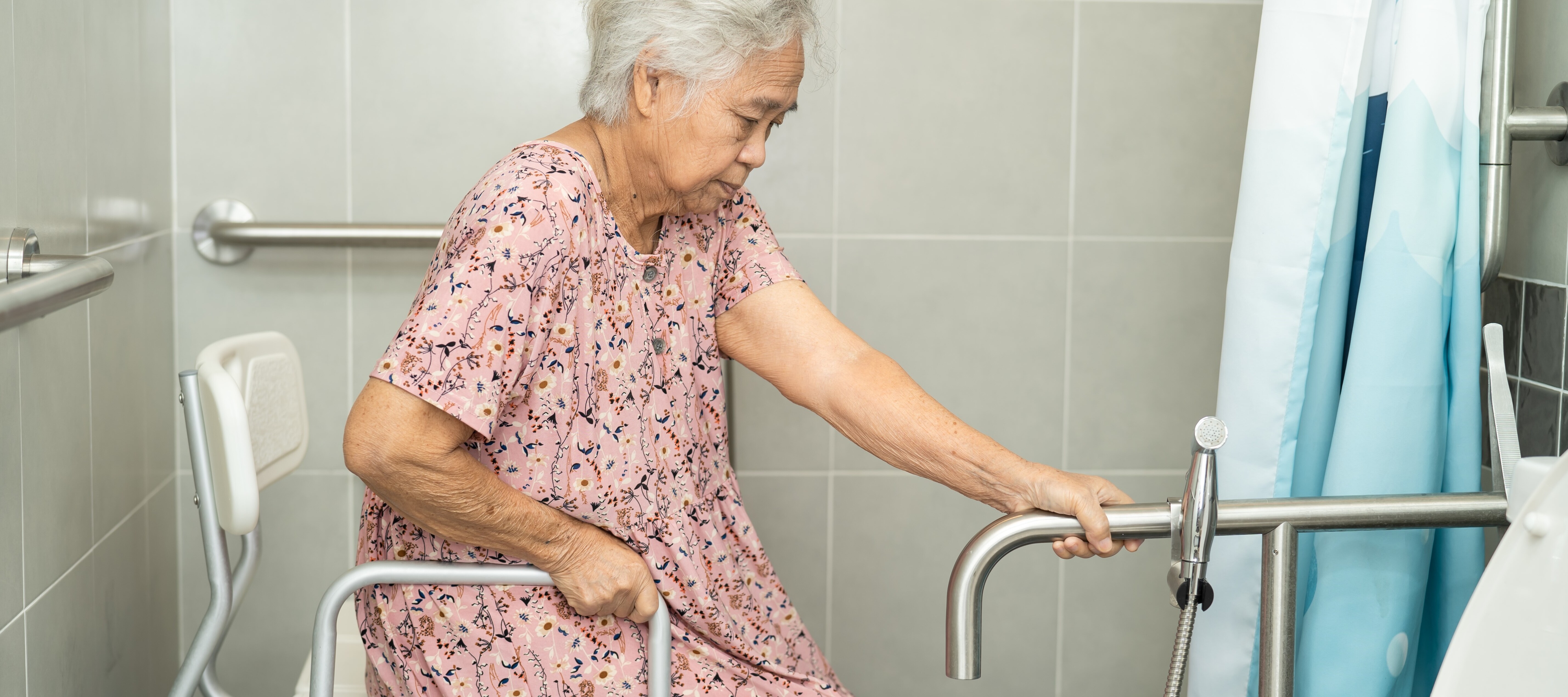 Elderly woman using a walk in shower and seat in her nightgown.