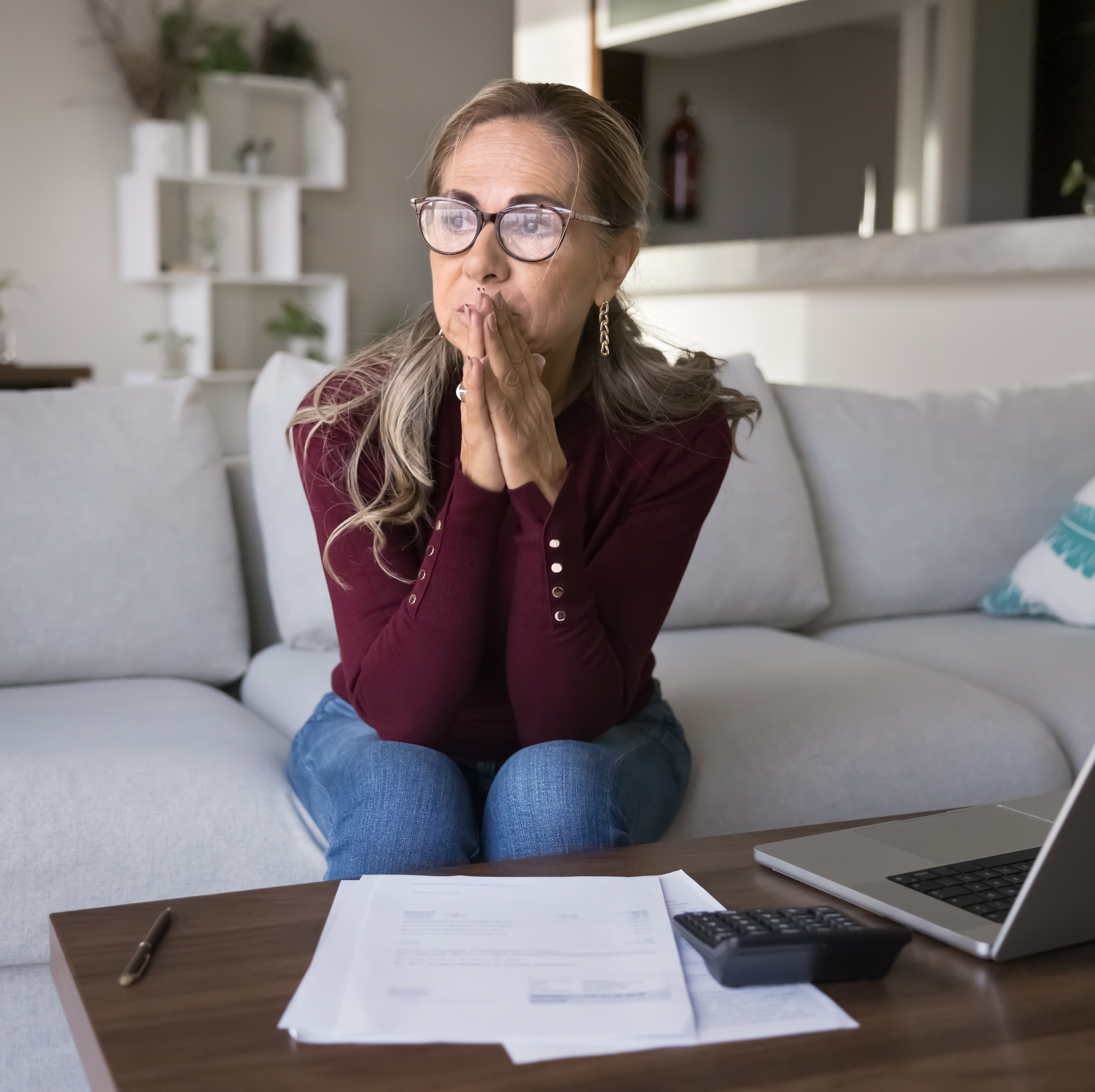 A concerned woman sits pensively in her living room.