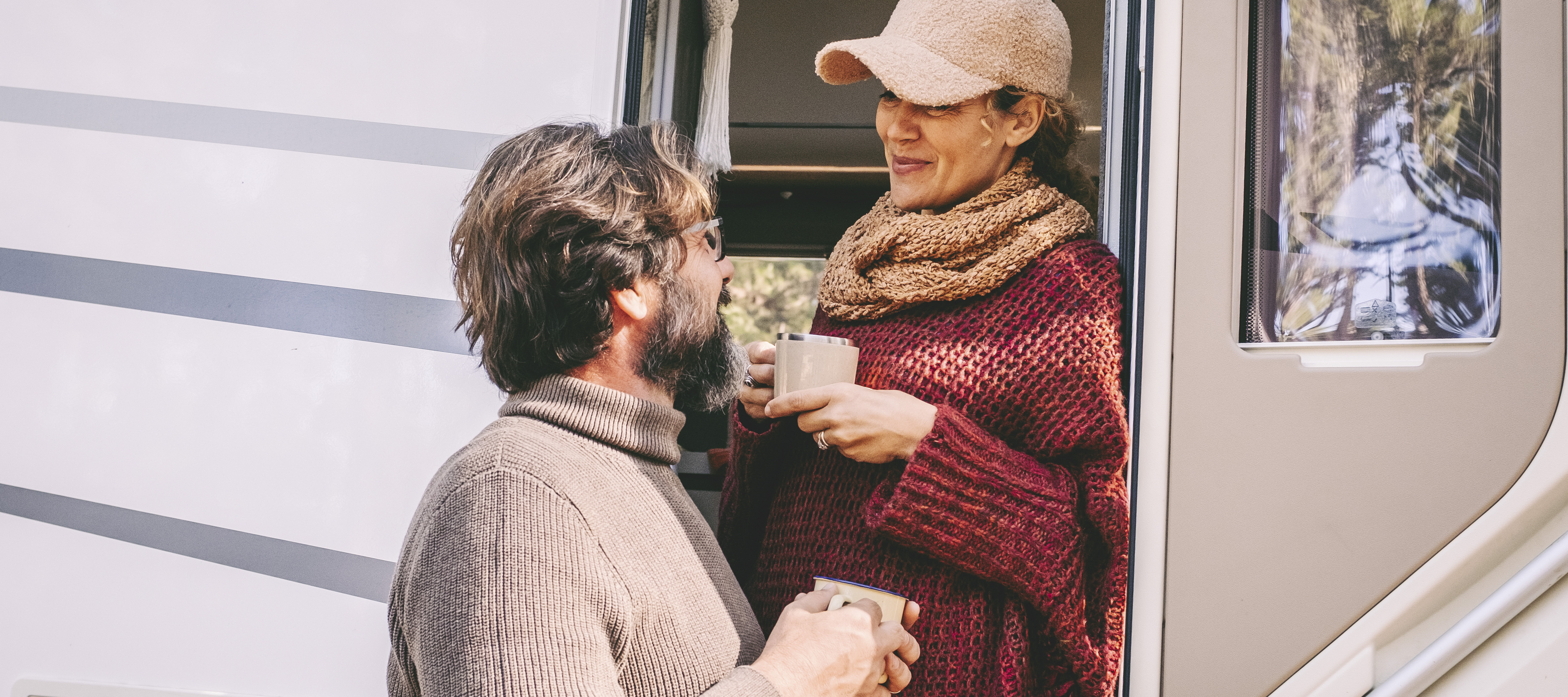 Middle-aged couple having coffee in doorway of their RV.