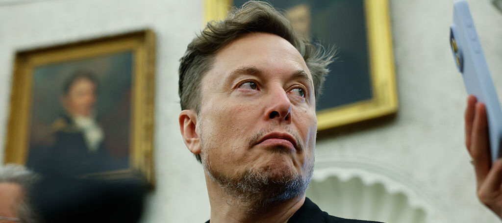 Elon Musk listens as reporters ask U.S. President Donald Trump questions during a press availability in the Oval Office.