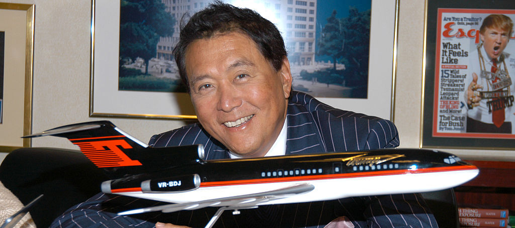 Robert Kiyosaki sitting at a desk with a toy model airplane.
