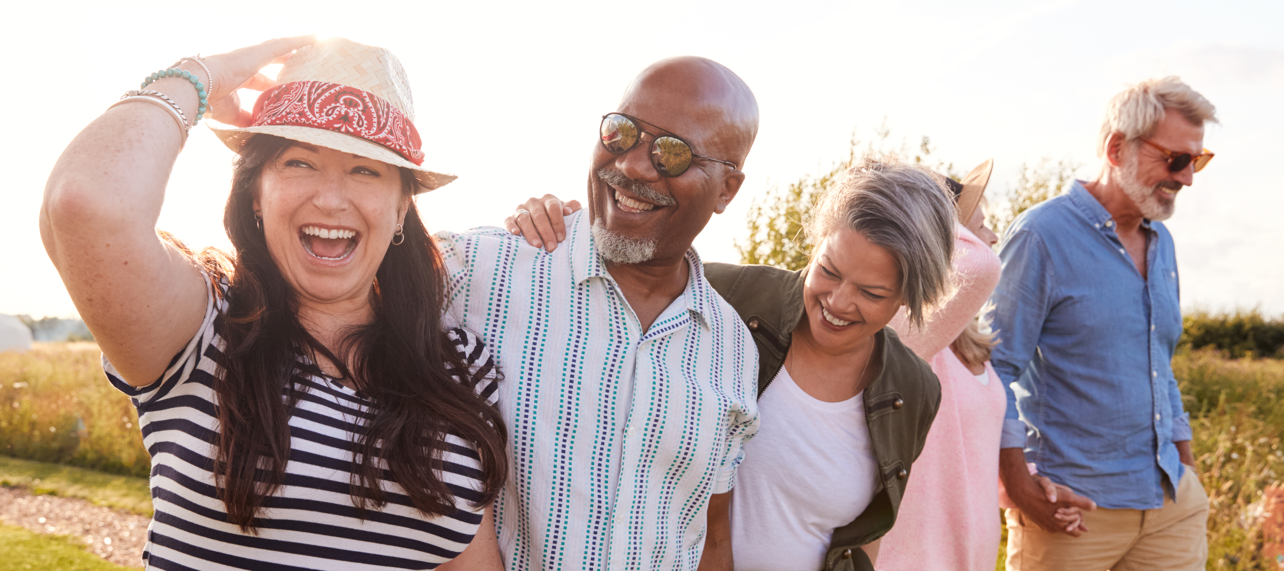 Group of mature friends laughing and smiling while walking together outside.